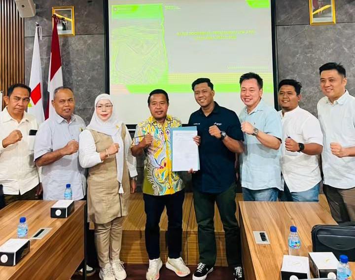 foto: 7 orang terdiri dari anggota Komisi II dan pihak Pertamina. Ada penyerahan dokumen surat resmi. Pose kepalan tangan = simbol solid dan komitmen. Background slide Pertamina menunjukkan ini rapat resmi koordinasi.